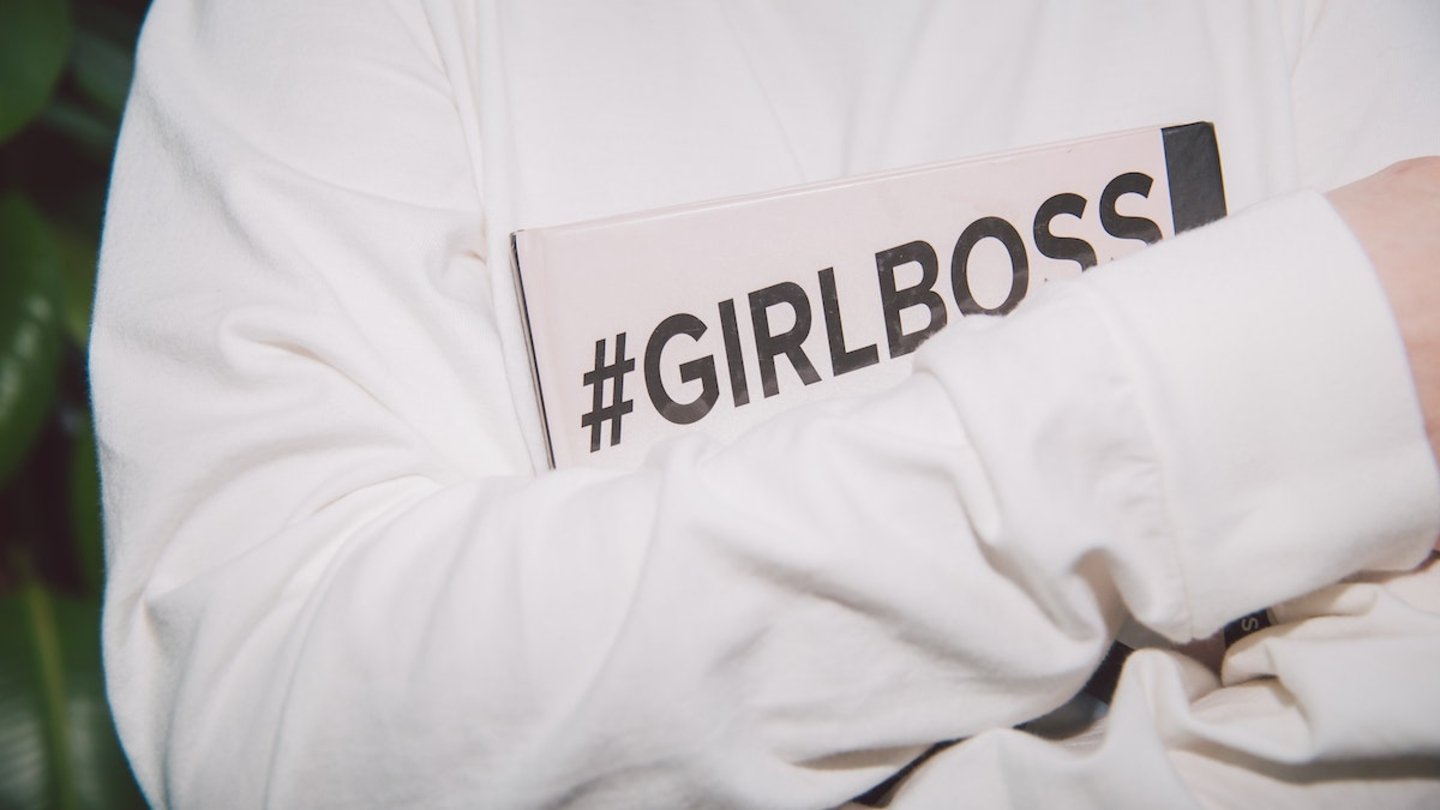 Una mujer sosteniendo una carpeta en la que pone #GirlBoss