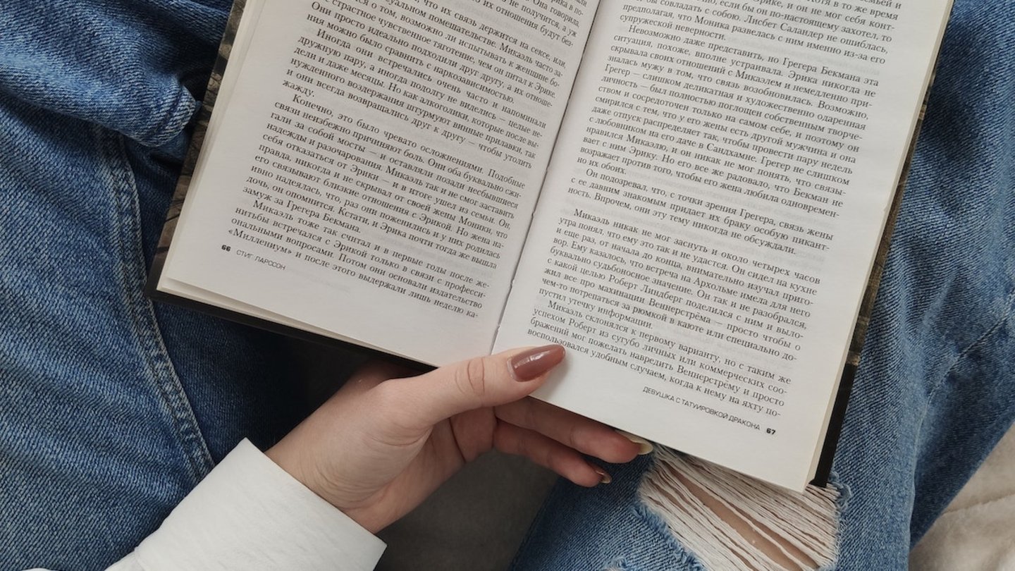 Una mujer sosteniendo un libro entre sus piernas